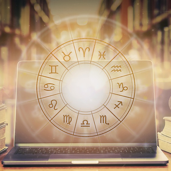 Glowing golden astrological wheel floating over a computer with shelves full of books in the background 