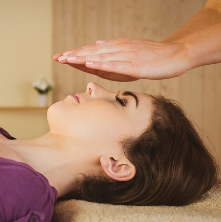 Woman receiving hands off Reiki over her face