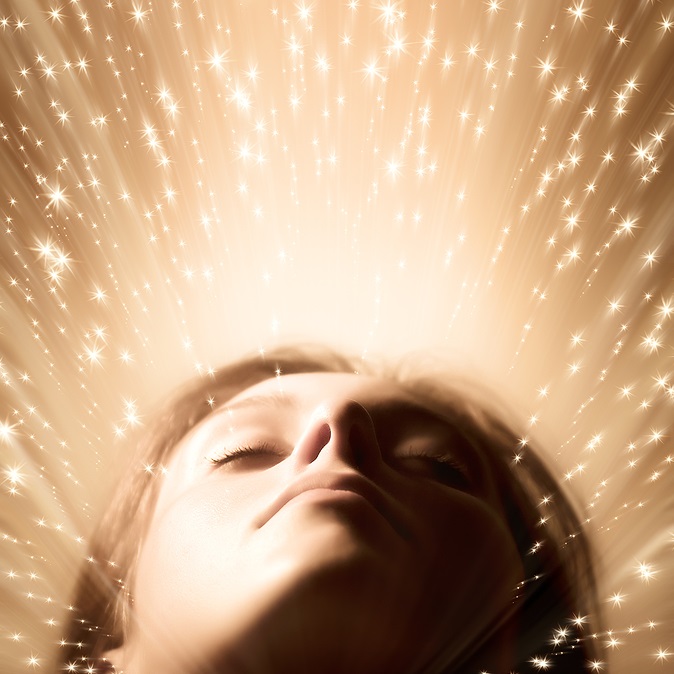 Woman looking upward surrounded by golden sparkling light