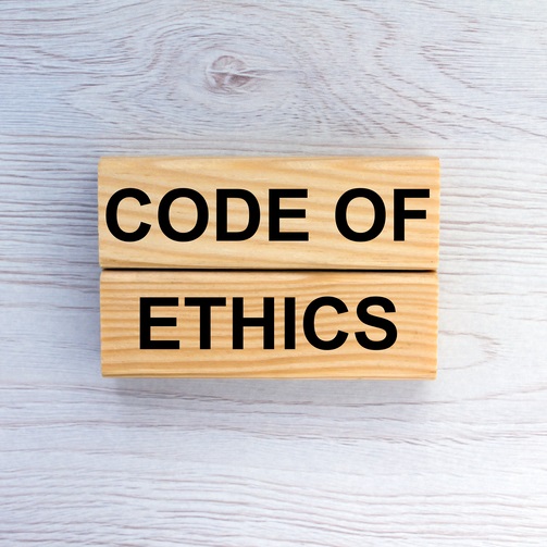 Wooden blocks displaying the words Code of Ethic against grey background