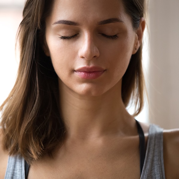 Peaceful face of a young woman with eyes closed meditating