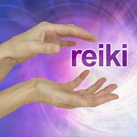 Hands facing each others with the word Reiki and while light between the hands against purple and blue background