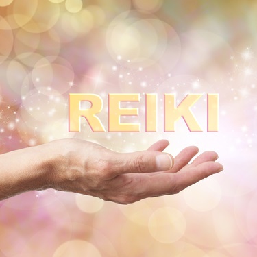 Open hand facing upward with the word Reiki and sparkles above it against background of golden orbs