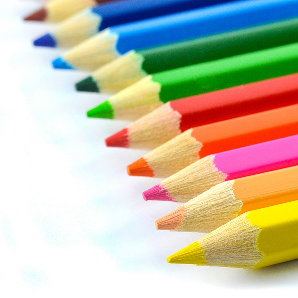 Colored pencils in a row in rainbow colors against white background