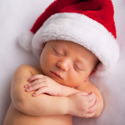 Photo of a sleeping newborn baby with arms crossed over chest