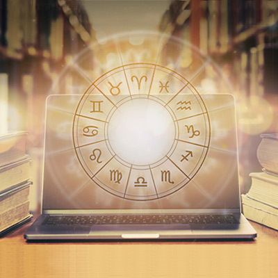 Golden astrological wheel floating over a computer with shelves full of books in the background